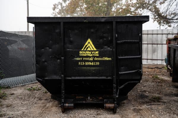 Branded South Vue Construction roll-off dumpster on a job site showing the company logo and phone number