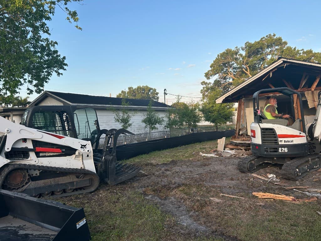 Skid steer and mini-excavator working a residential demolition site at sunrise
